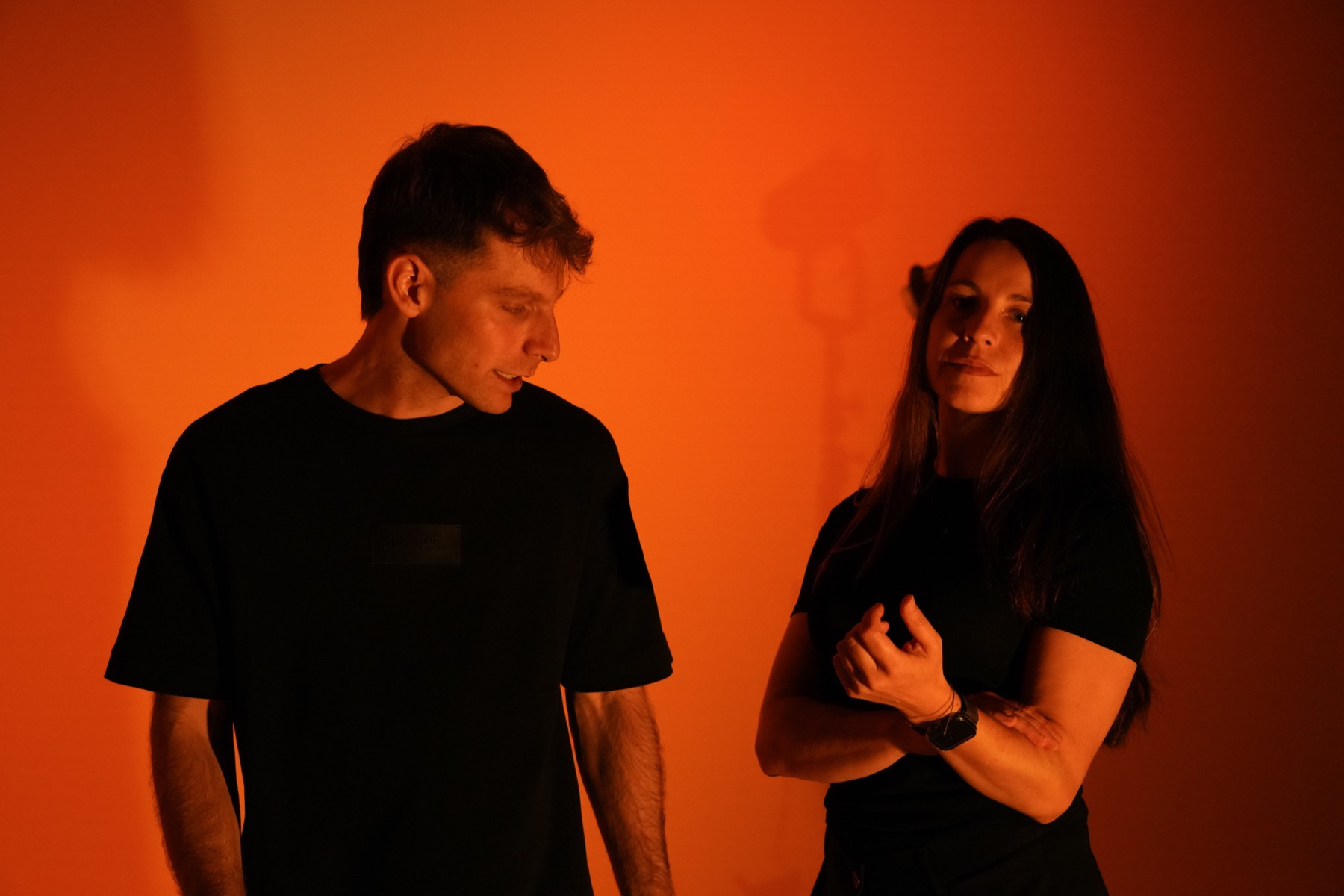 Dos miembros del equipo en el estudio iluminados por una luz naranja