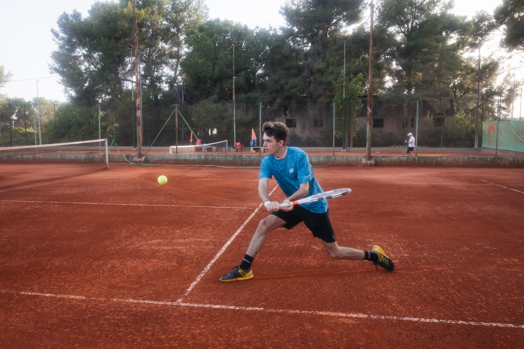 Jugador de tenis ejecutando un golpe sobre una pista de tierra batida